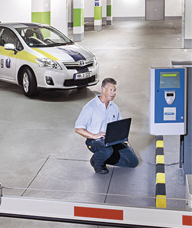 Ein Mitarbeiter der Vollmergruppe Parking bei der Problemlösung am Einlassautomaten eines Parkhauses mit dem Laptop.