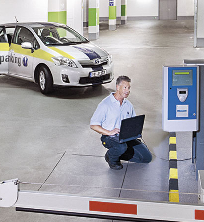 Ein Mitarbeiter der Vollmergruppe Parking bei der Problemlösung am Einlassautomaten eines Parkhauses mit dem Laptop.