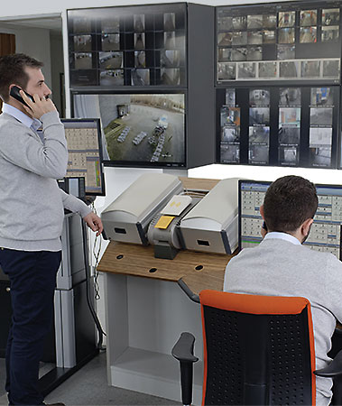 Zwei Mitarbeiter der Vollmergruppe Parking vor den Überwachungsmonitoren in der Service-Leitstelle.