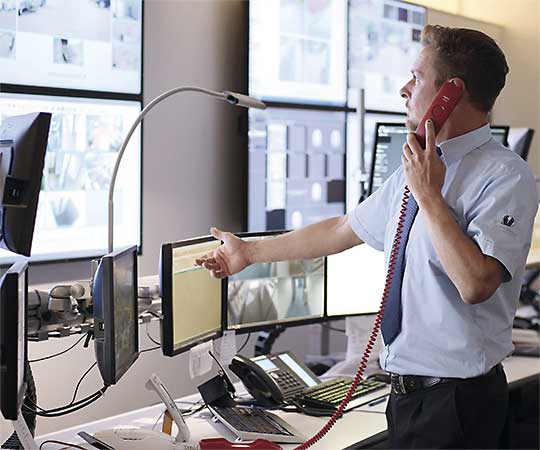 Ein Mitarbeiter der Vollmergruppe Security vor den Überwachungsmonitoren in der Notruf- und Service-Leitstelle.