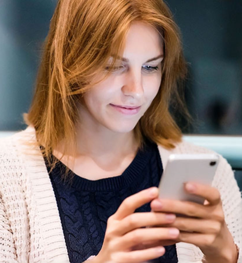 Eine junge Frau informiert sich über die aktuellen Stellenangebote der Vollmergruppe Dienstleistung auf ihrem Smartphone.